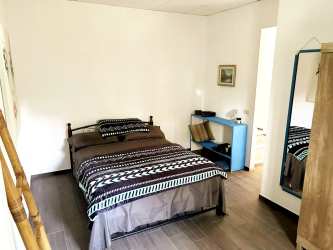 Simple bedroom with wood floor, mirror, and bookshelf countryside home Las Tablas Panama