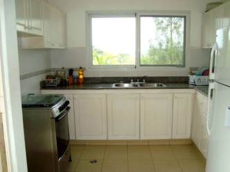 Shared kitchen area with white cabinets, granite counters and window in Panama Oeste rental