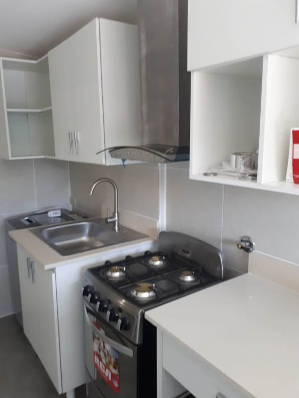 Compact modern kitchen with white cabinets, gas stove in Canal Zone Panama