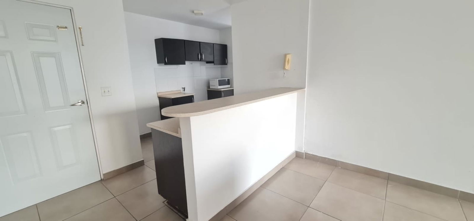 Spacious living room with wood panel wall and tile floors in PH Metric Apartment