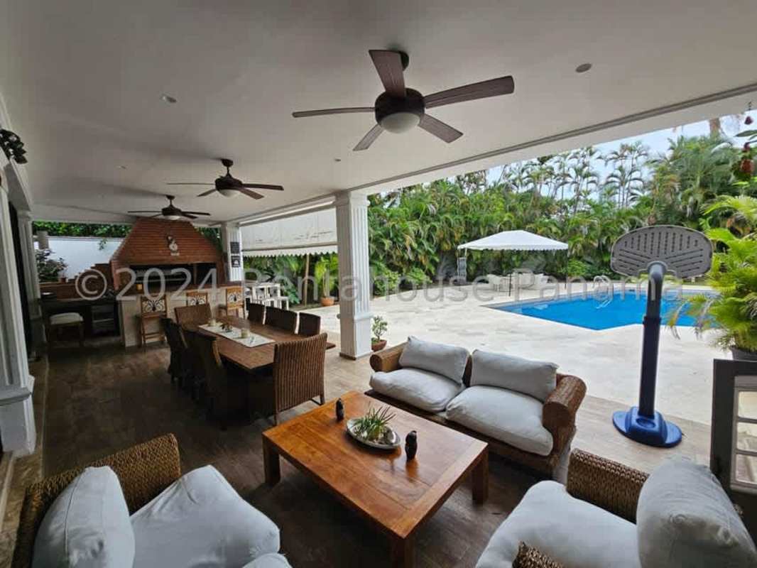 Outdoor swimming pool surrounded by tropical garden and covered patio in Altos del Golf luxury home Panama