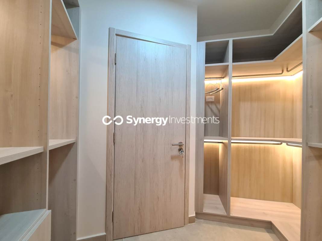 Modern bedroom with large bed, walk-in closet, mounted TV, city view at Santa Maria Golf Panama