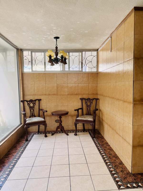 Indoor lounge with traditional wooden chairs, tiled walls and chandelier in La Cresta Panama City