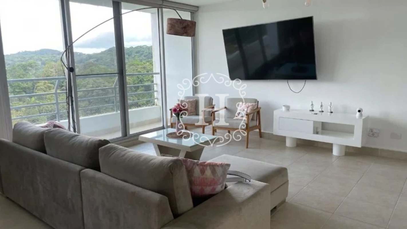 Modern living room with large sliding glass doors leading to balcony with nature views at PH Clayton Park I Panama City