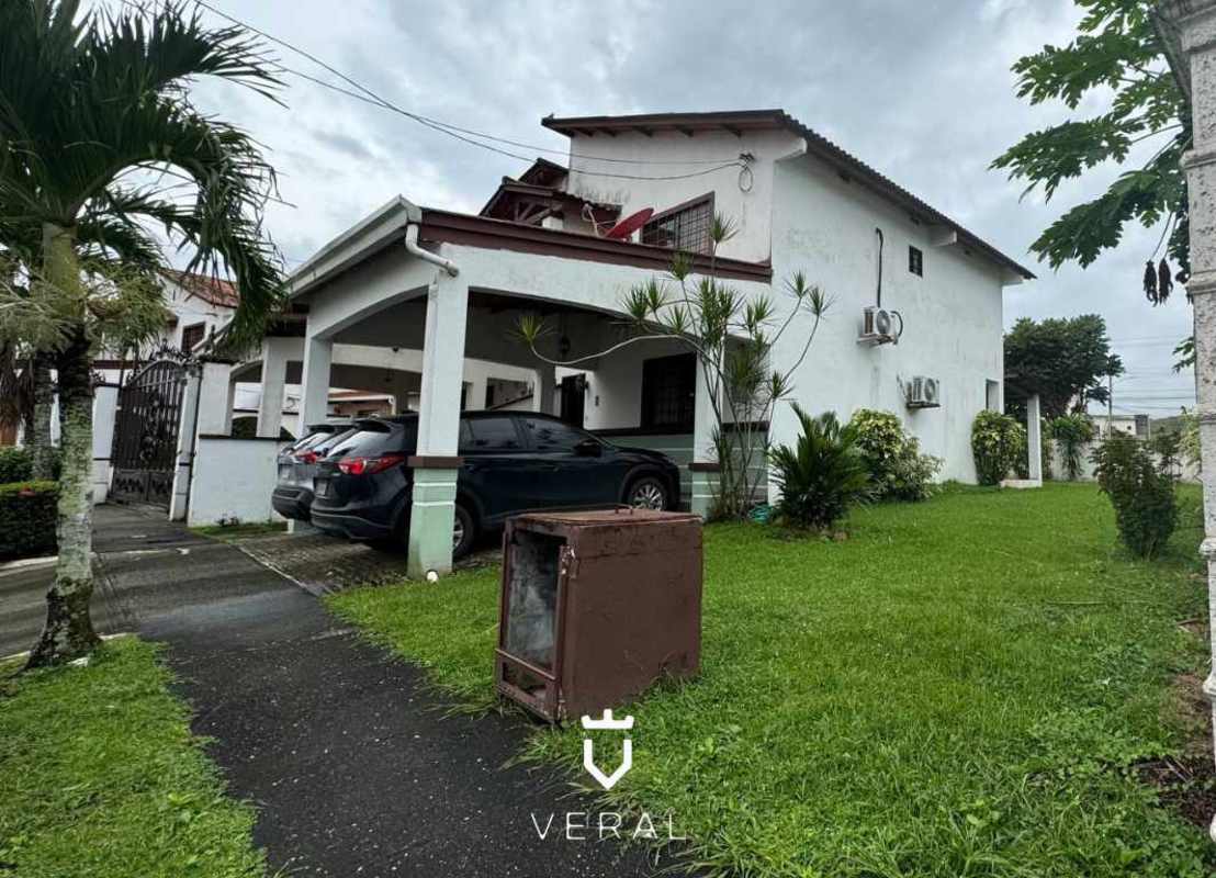 Spacious backyard with green grass and plants behind two-story house Panama for sale