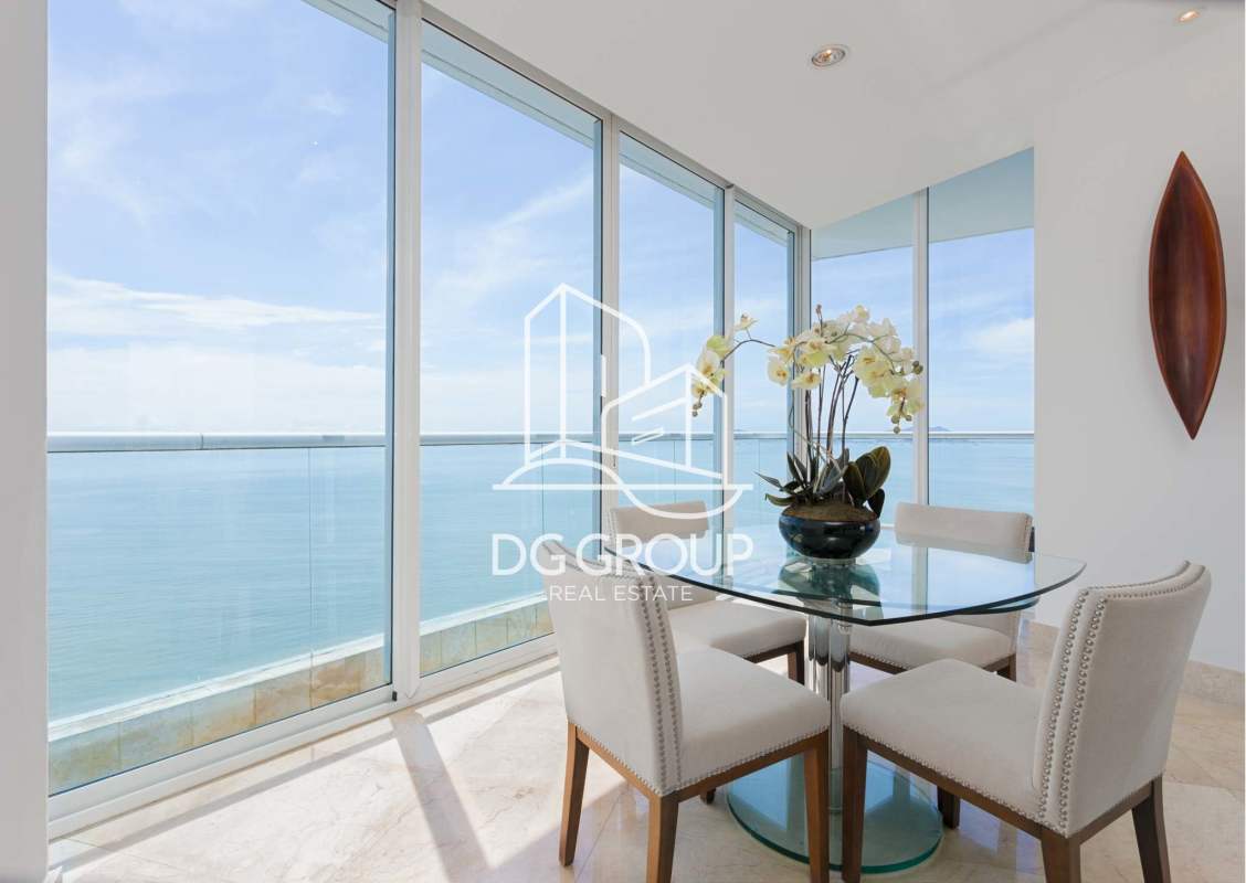Glass dining table with upholstered chairs and panoramic views at PH The Point Punta Paitilla Panama