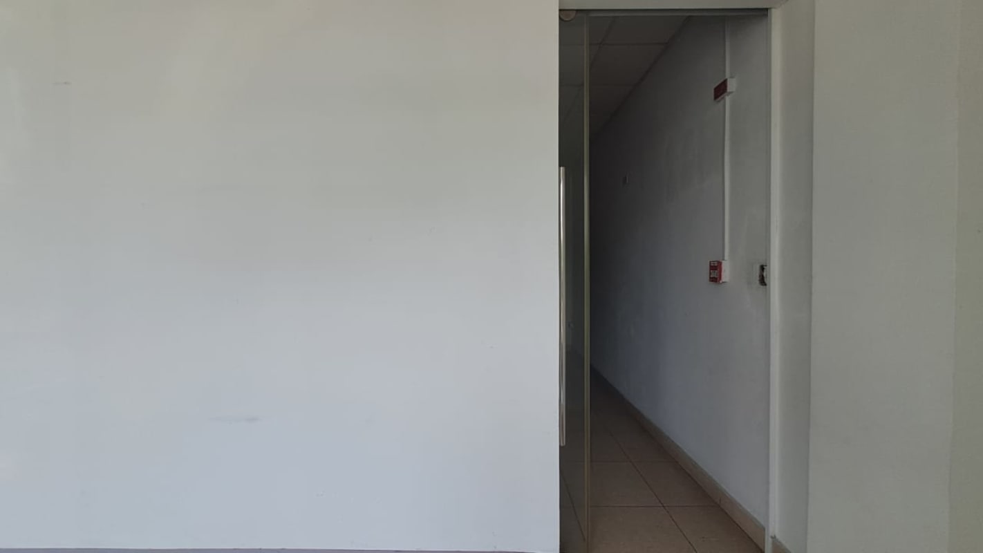 Bright corridor with glass door and white walls inside PH Green Plaza Costa del Este