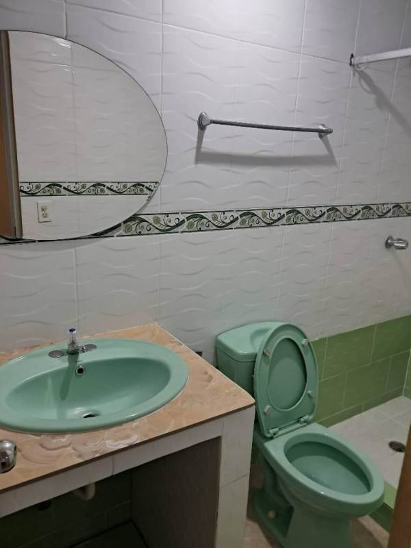 Bathroom with green ceramic sink, toilet, beige countertop, decorative tiles rental Panama City