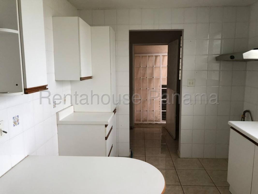 Simple kitchen with white tiles, cabinets, and window Brisas del Golf Panama