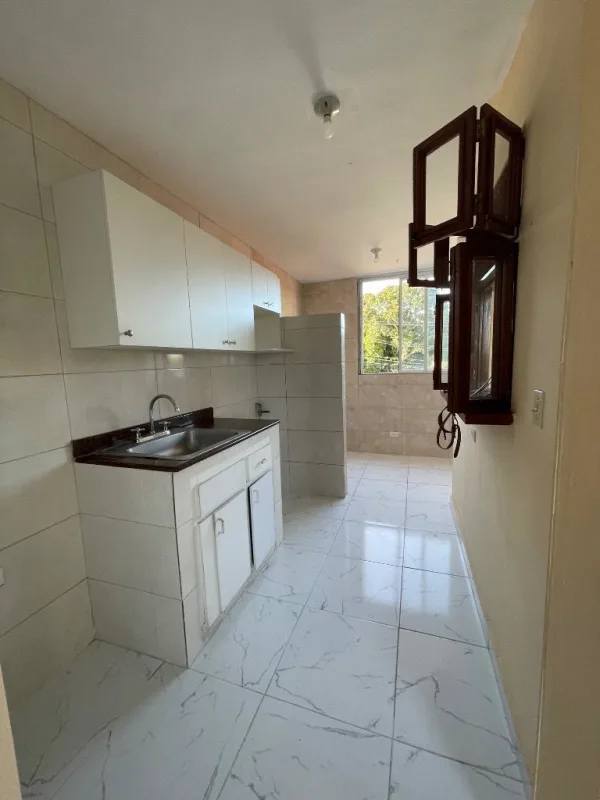 Bright kitchen with white tile flooring, cabinets, and marble countertop in Panama apartment