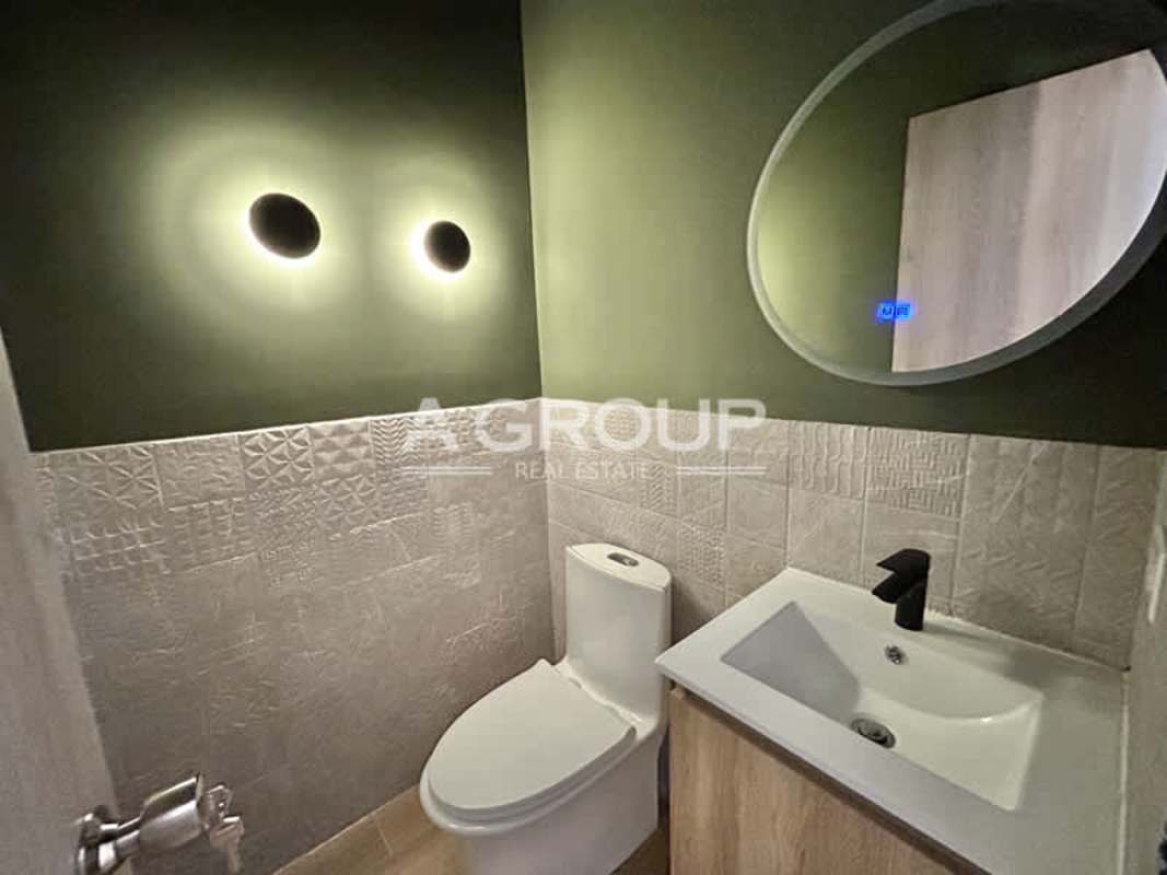 Contemporary compact bathroom with olive green textured tiles, backlit mirror Financial Park Panama