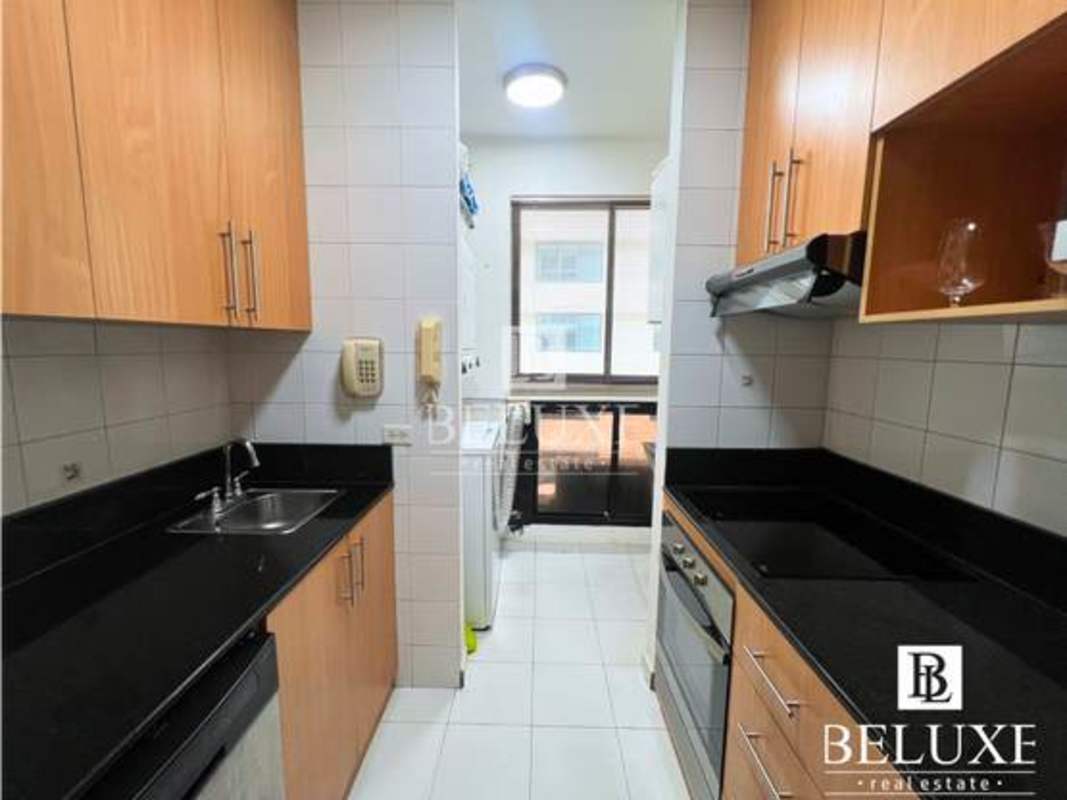 Kitchen with black granite counters, wooden cabinets, full appliances and washer dryer in PH Royal Center Marbella Panama