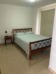 Bedroom with wooden bed, tile floor, minimalist decor in villa at Ibiza Beach Residences Río Hato
