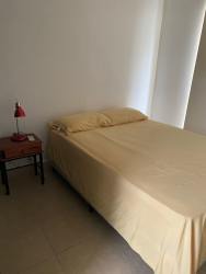 Minimalist bedroom with beige bedding, red lamp, in Ibiza Beach Residences villa Rio Hato Panama