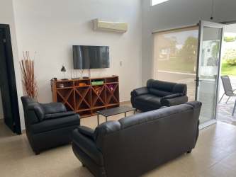 Living room with black leather sofas, media console, access to outdoor terrace Rio Hato Panama