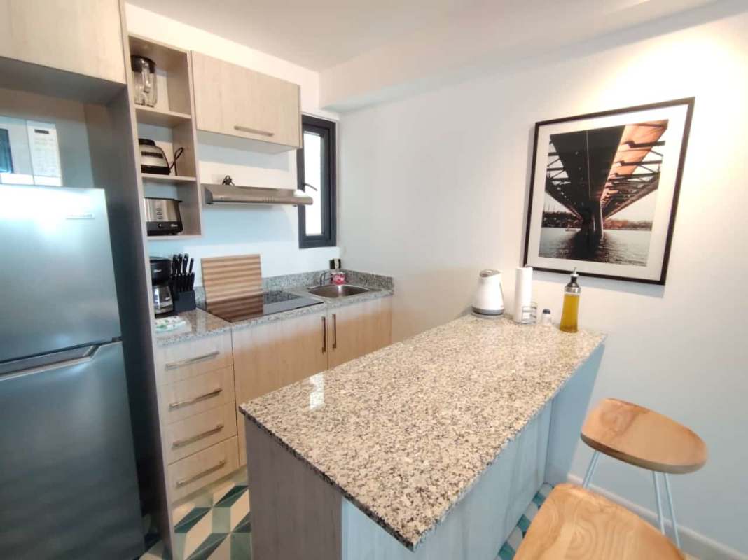 Studio for rent with open kitchen, red sofa, geometric floor tiles at PH La Manzana Casco Viejo Panama