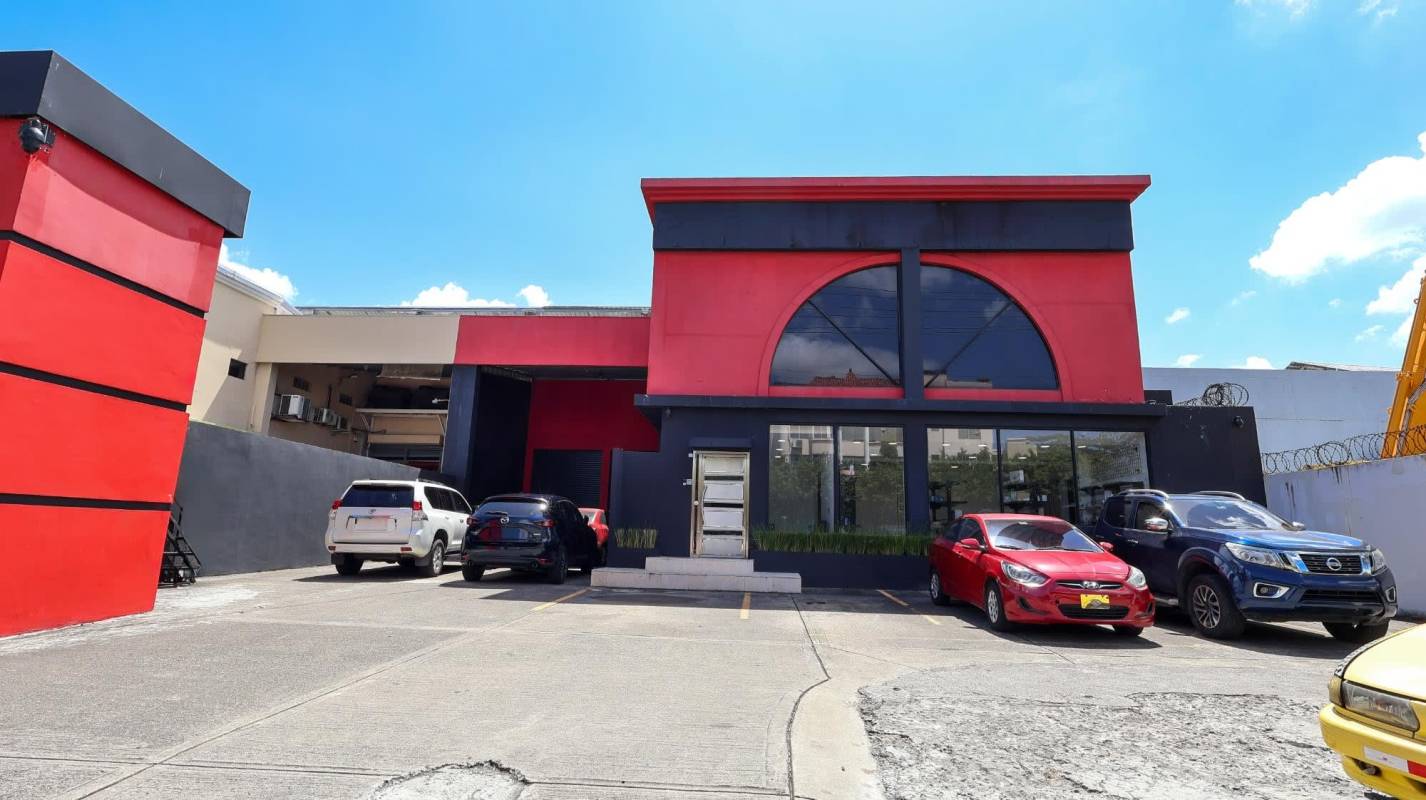 Contemporary commercial facade with large window, red and black accents and parking Costa del Este Panama