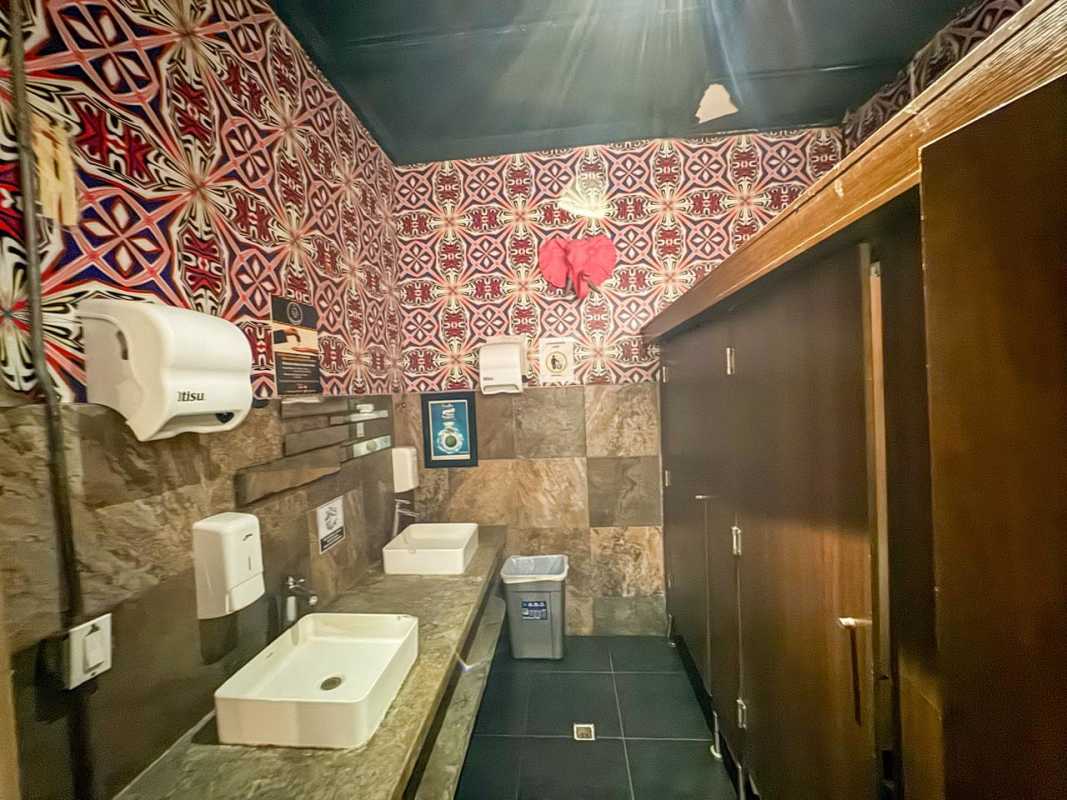 Eclectic commercial restroom with wallpaper, dual sinks, and stone accents in Casco Viejo
