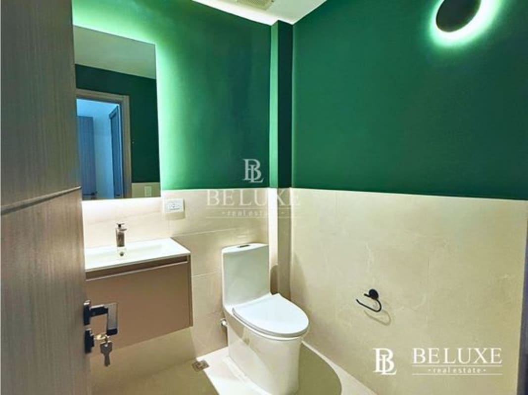 Minimalist bathroom with green wall, white tile, and modern sink in Financial Park Costa del Este office rental Panama