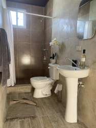 Modern bathroom with walk-in tiled shower, pedestal sink and natural light in Boquete Panama