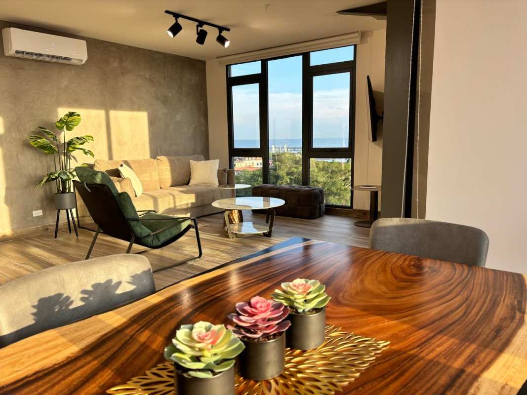 Stylish living dining area with large panoramic windows, sea view, and concrete accent at PH Casco View Casco Viejo