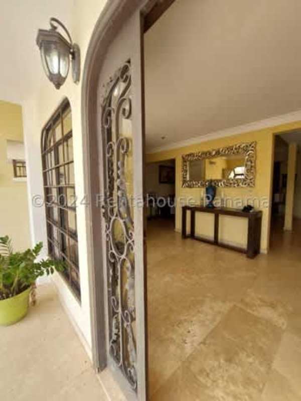 Outdoor pool area with brick patio, gazebo, and lush gardens in Las Cumbres gated community Panama