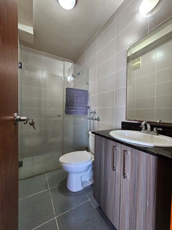 Bright living room with sofa, TV, window overlooking Parque Omar in PH Residencias del Sol Panama City