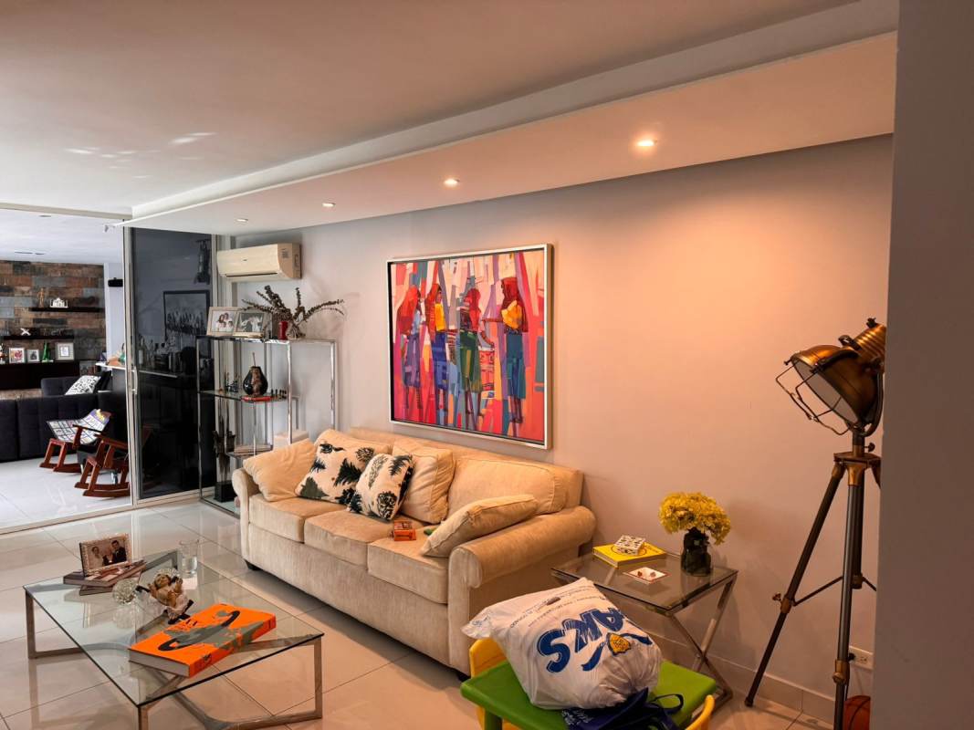 Living room with comfortable seating, glass coffee table, artwork and large windows in Hato Pintado home for sale