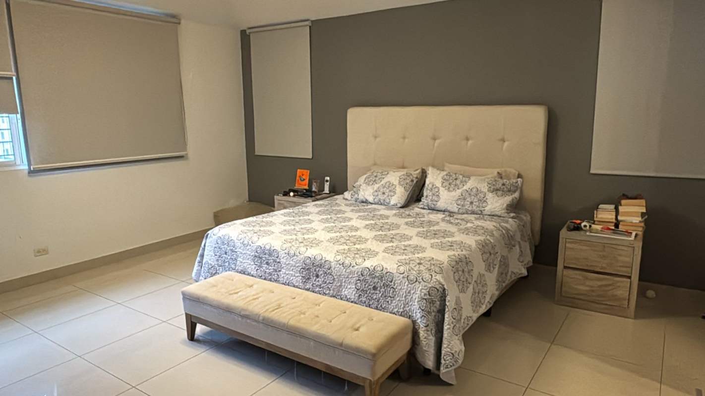 Master bedroom with gray accent wall, upholstered bed, tile flooring in Los Guayacanes