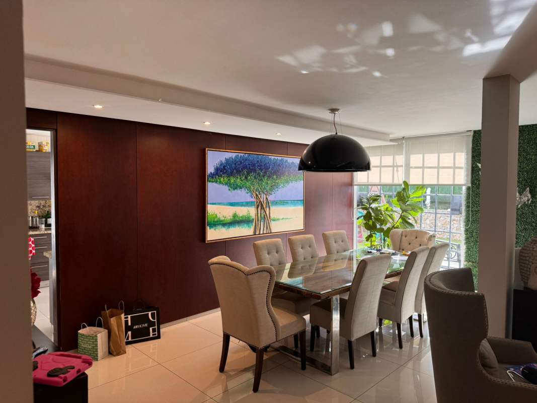Dining room with glass table, pendant lamp, wood accents, and garden view in Los Guayacanes home