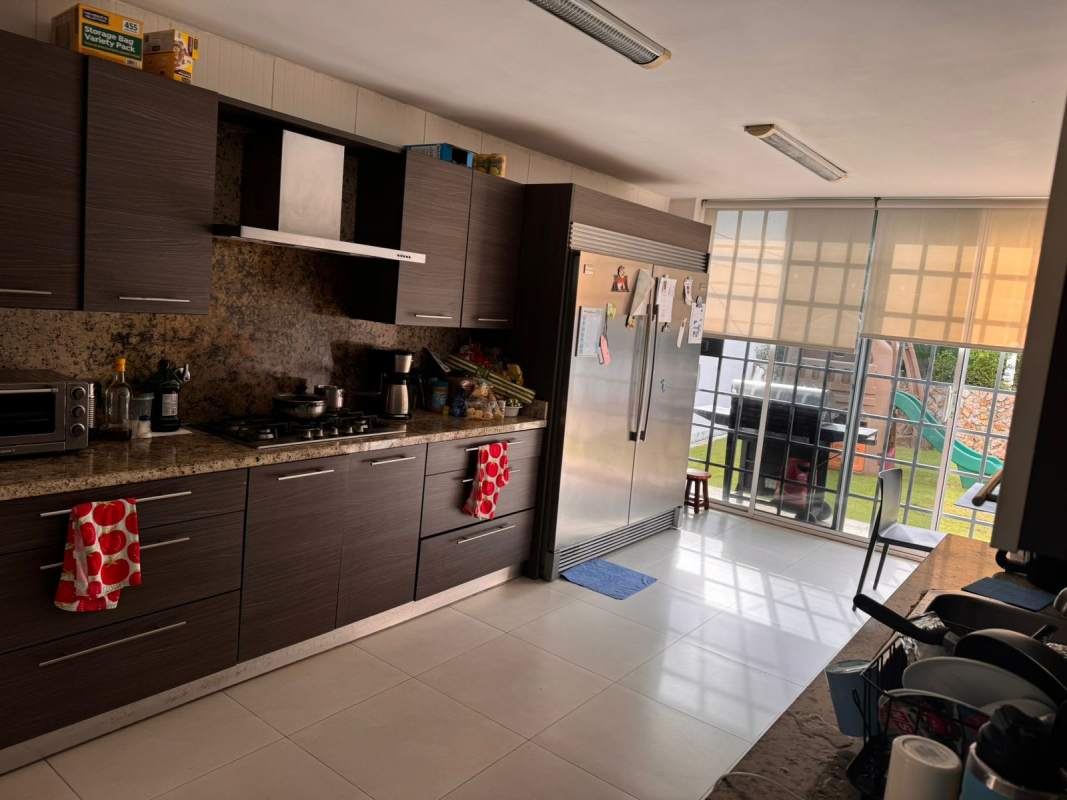 Kitchen with dark cabinetry, granite counters, stainless appliances and glass doors to garden in Panama home