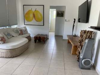 Minimalist dining room with glass table, white chairs, large window at Bijao Beach Club Panama