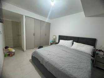 Modern bedroom with large bed, built-in wardrobe, neutral gray tones Las Villas de Arraiján Panama