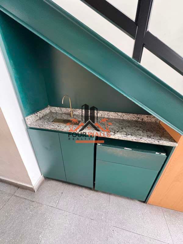 Compact teal kitchenette area with marble counter under staircase in commercial property Panama