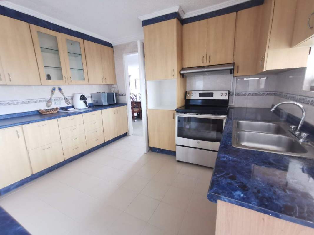 Kitchen with ample wood cabinets, tiled counters and backsplash in PH Fuente de los Cibeles Panama City