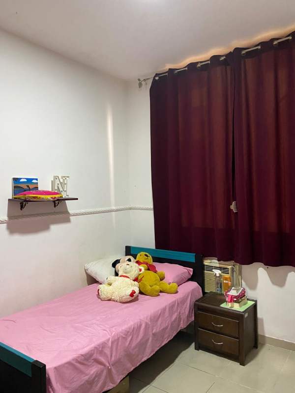 Simple single bedroom with pink bedspread, dark curtains PH Miraflores Betania