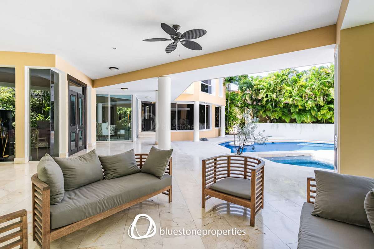 Covered outdoor terrace with pool view and lush gardens in luxury villa Altos del Golf Panama City