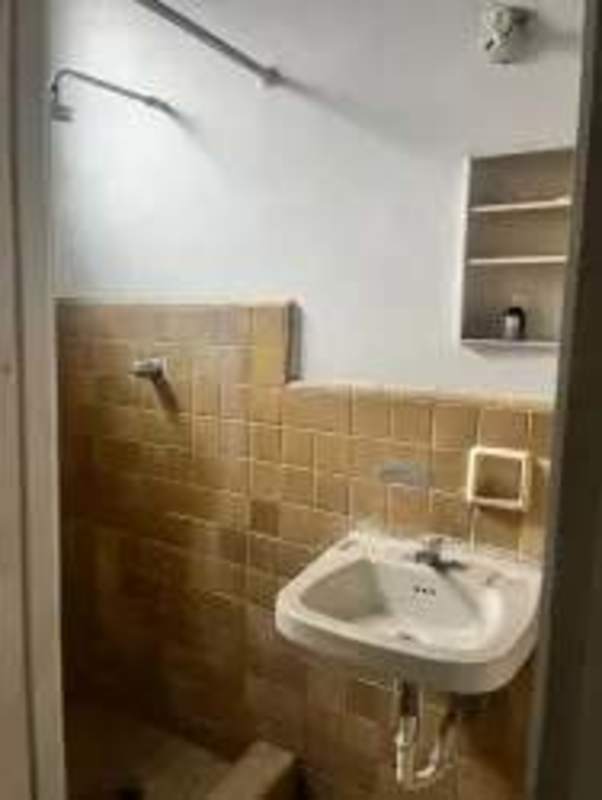 Simple kitchen with white cabinets, cement sink, tiled backsplash in Santa Ana mixed-use building Panama