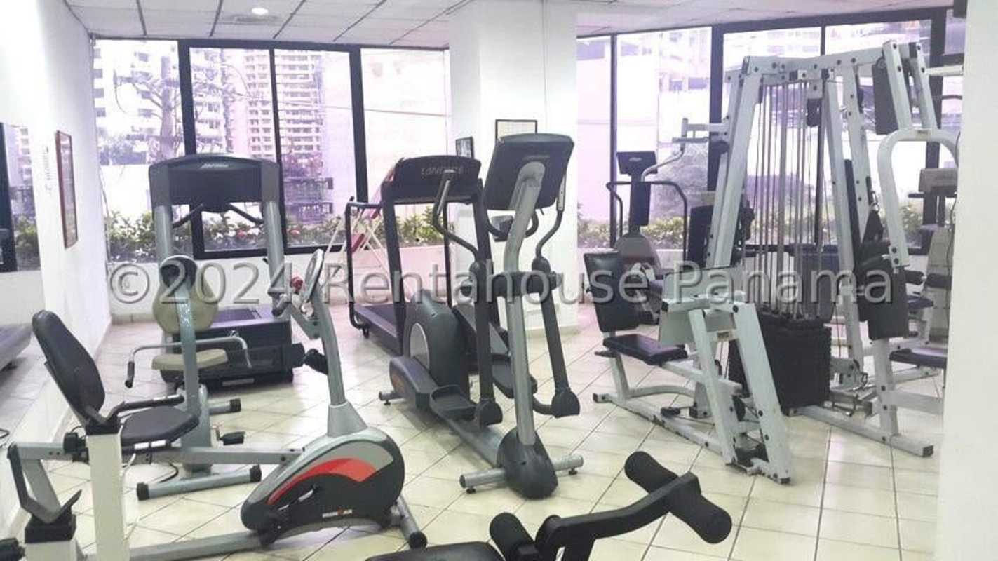 Modern gym with cardio equipment and large windows facing the skyline in PH Punta del Sol Panama