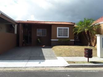 Single-story brown house with driveway, front lawn, security bars and red tile roof in Costa Verde Panama
