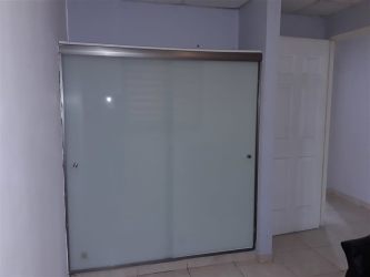 Backyard with patio, BBQ, green area bordered by brown wall at Arboledas La Chorrera Panama