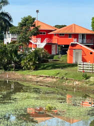 Bright orange villa structures with pond and greenery on private ranch property for sale Panama