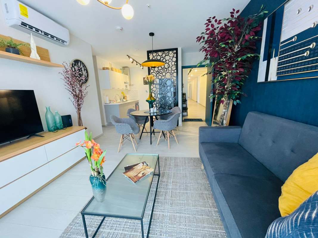 Modern living room with navy wall, gray sofa, dining area, indoor plants in PH Demetra Parque Lefevre