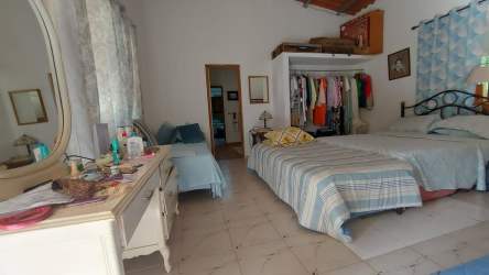 Rustic style bedroom with tile floors, high ceiling with beams, bed, and AC unit in countryside Penonomé Panama