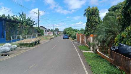 Suburban residential street with parked cars fences and vegetation La Chorrera