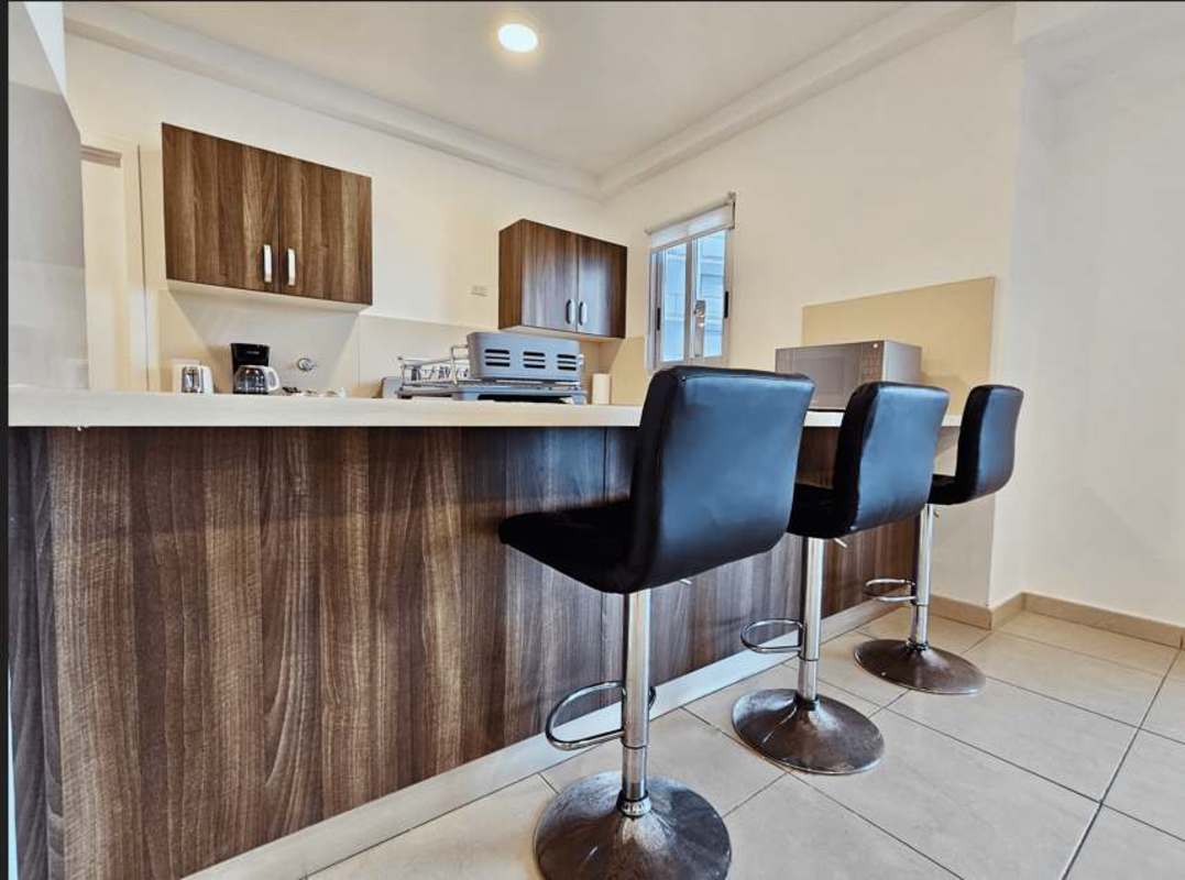 Contemporary kitchen with wood cabinetry and breakfast bar in PH Oasis Punta Pacífica