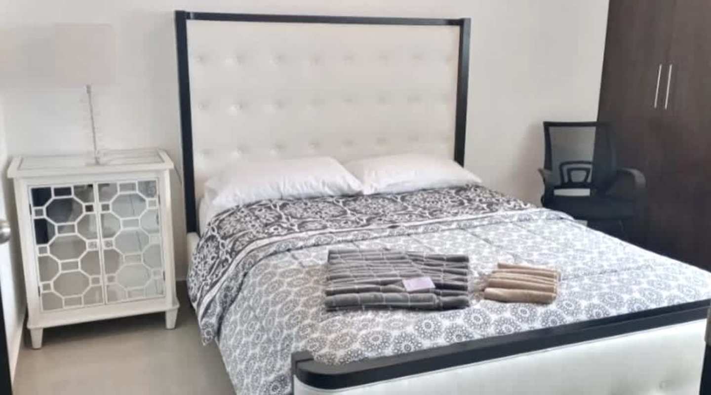 Large bedroom with modern design, tufted bed, mirrored nightstand at PH Miramar Marina, Panama City