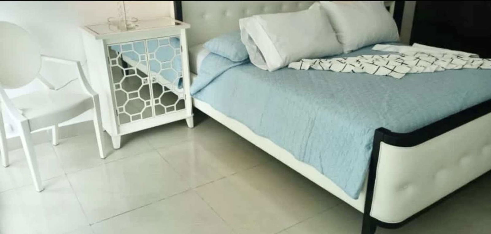 Minimalist bedroom with white bed, light blue accents, mirrored nightstand at PH Miramar Marina