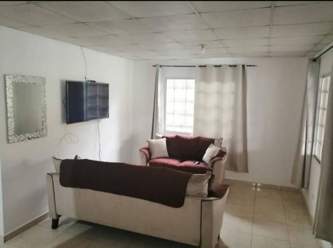 Simple living area with sofas wall TV beige curtains Villa Verona Panama