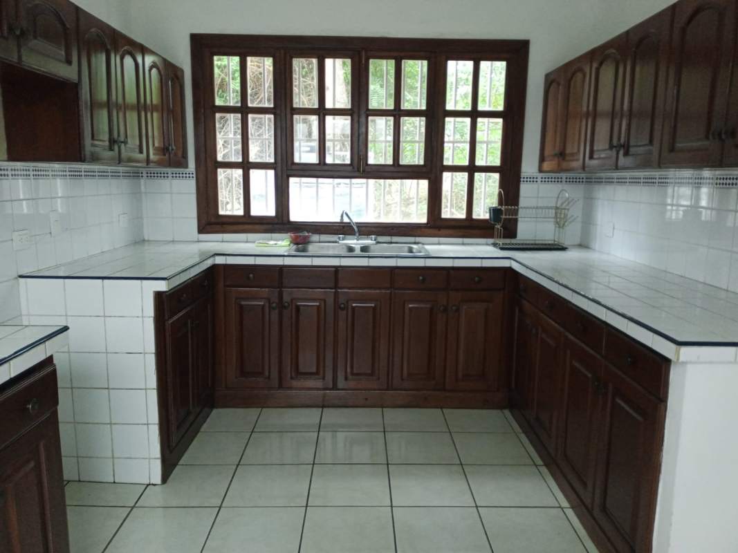 Living room area with tiled floor, large windows, white walls in Santa Anita Managua house for sale